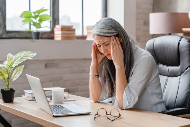 Tired sad mature business woman having headache in office