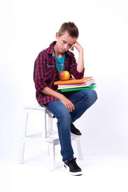 tired schoolboy European appearance in shirt and jeans sitting 