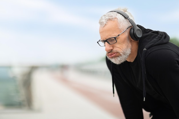 Tired senior man take break while exercising outdoor copy space