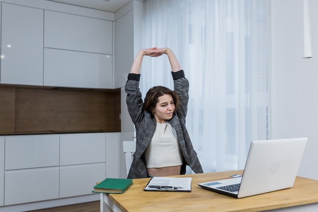 Tired and sleepy woman working on a laptop, at home or office, working online