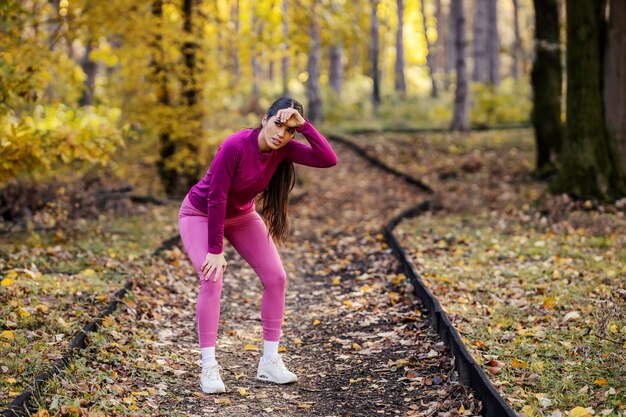 A tired sportswoman is taking a break from fitness in nature