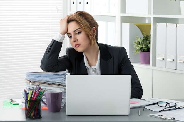 Tired stressed business woman sitting with huge pile of papers