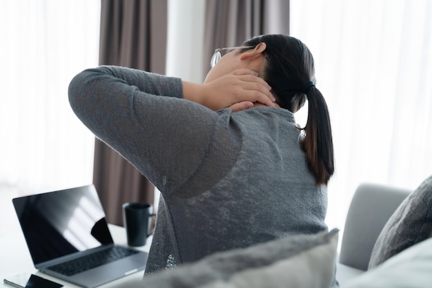 사진 소파에 앉아 집에서 일하는 섬유근육통 목 통증으로 고통받는 피곤한 비즈니스 여성