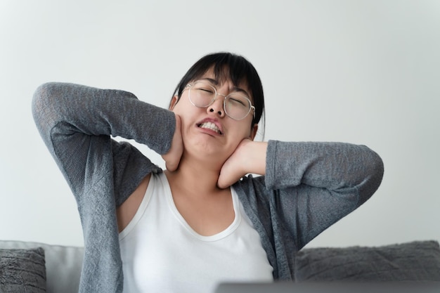 소파에 앉아 집에서 일하는 섬유근육통 목 통증으로 고통받는 피곤한 비즈니스 여성