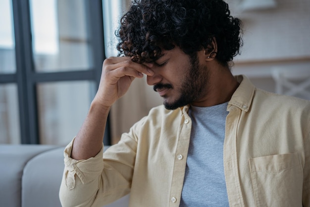 Photo tired stressed indian man having headache feeling sick sitting at home man fired from work