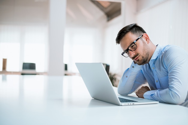 Tired student or businessman working with laptop in the office