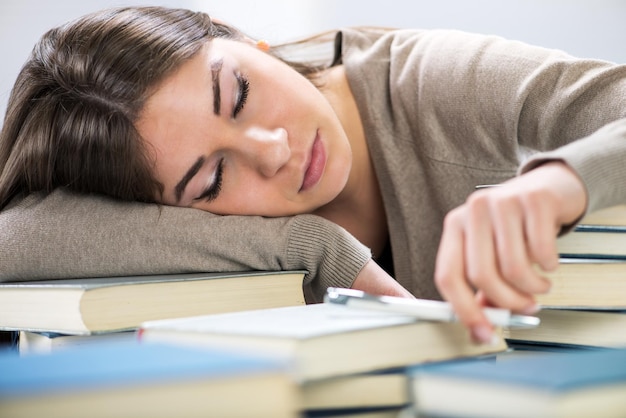 疲れた学生は、学びながら多くの本の間に眠りに落ちました。