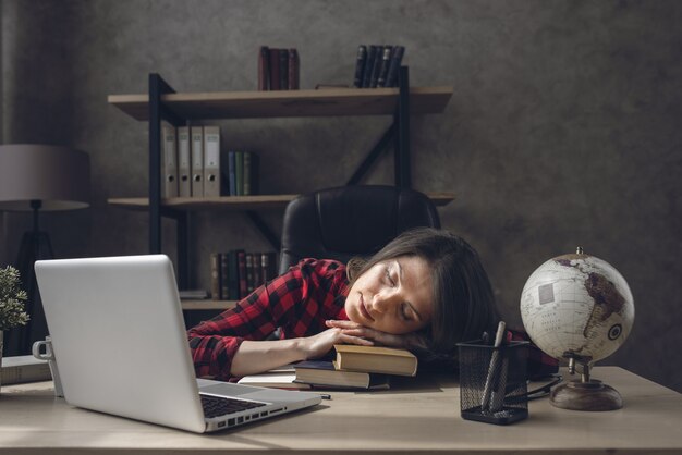 Tired student girl is sleeping over her books at home