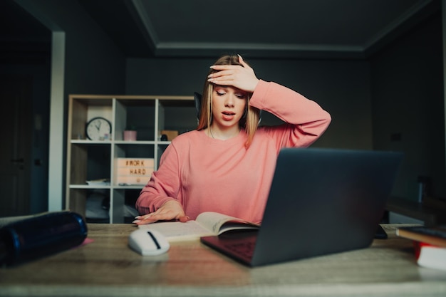 Foto studenti stanchi studiano a casa con un laptop guarda in un taccuino con una faccia sorpresa