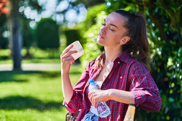 Donna sudorazione stanca che riposa all'ombra mentre in un parco nella stagione calda