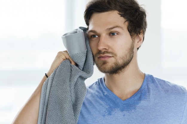 Photo tired sweaty man with a towel after fitness workout in the gym