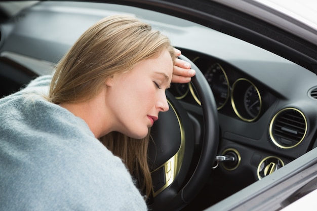 Tired woman asleep on steering wheel 