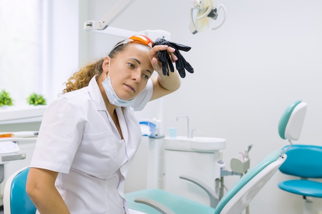 Tired woman dentist, background dental office chair