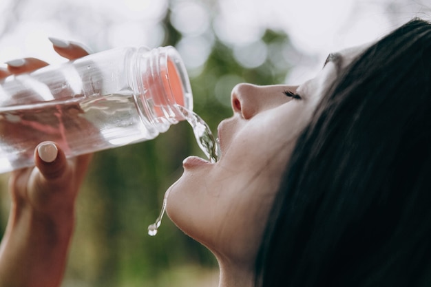 写真 トレーニング後に疲れた女性が水を飲む