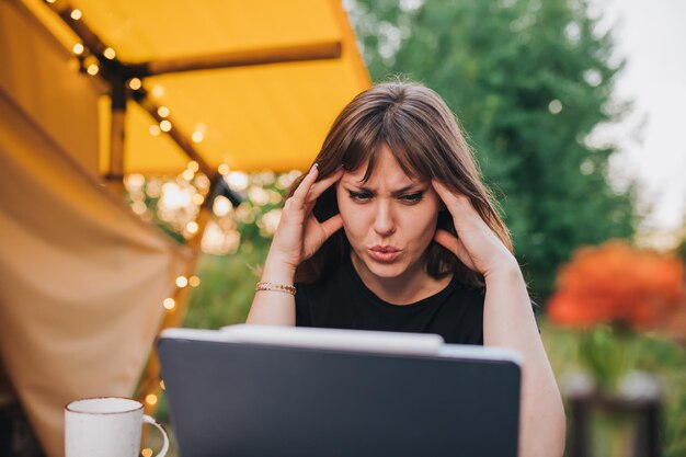 Tired Woman freelancer using a laptop on a cozy glamping tent in a sunny day Luxury camping tent for outdoor summer holiday and vacation Lifestyle concept