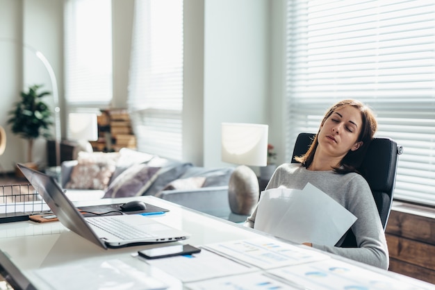 Tired woman at her desk is resting from work.