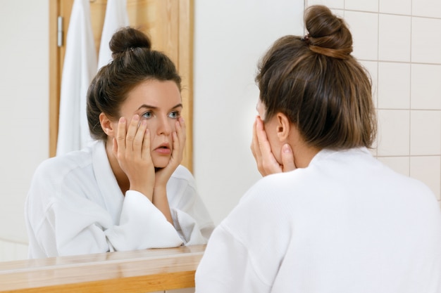 Tired woman is looking into the mirror