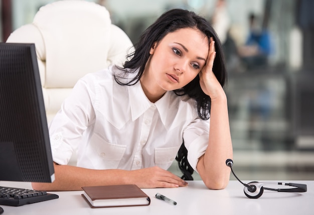 La donna stanca è seduta al tavolo di lavoro in un call center.