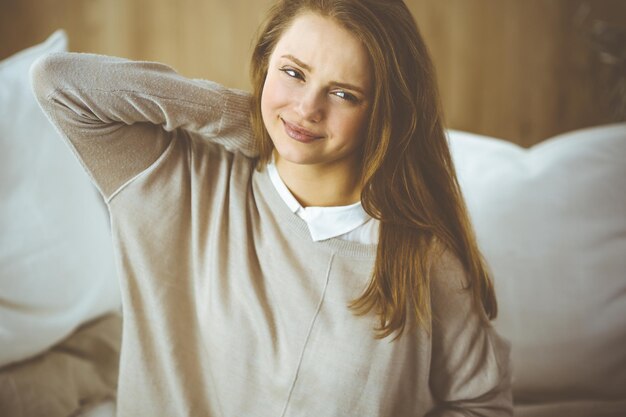 Tired woman massaging rubbing stiff sore neck tensed muscles fatigue from computer work in incorrect posture. Stay at home concept during Coronavirus pandemic and self isolation quarantine.