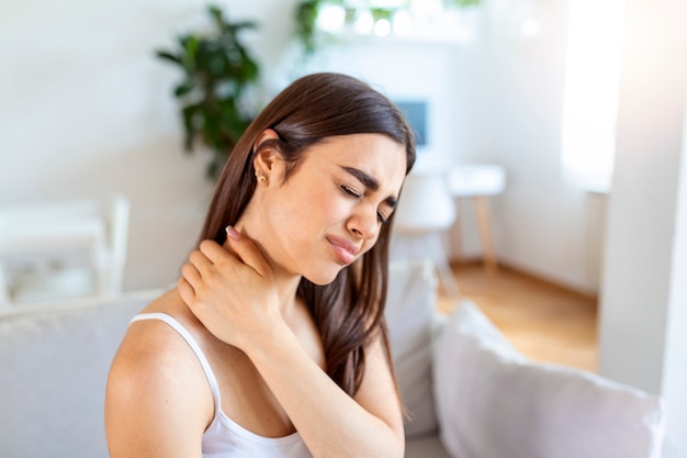 Tired woman massaging stiff sore neck, tensed muscles fatigued from computer work in incorrect posture while feeling hurt joint shoulder back pain ache. Fibromyalgia concept