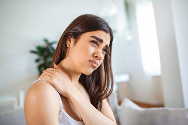 Tired woman massaging stiff sore neck tensed muscles fatigued\
from computer work in incorrect posture while feeling hurt joint\
shoulder back pain ache fibromyalgia concept