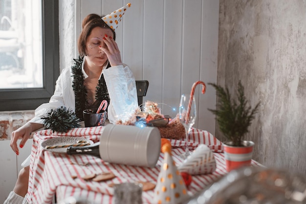 自宅で大晦日を祝った後、二日酔いと頭痛でパーティーハットに疲れた女性