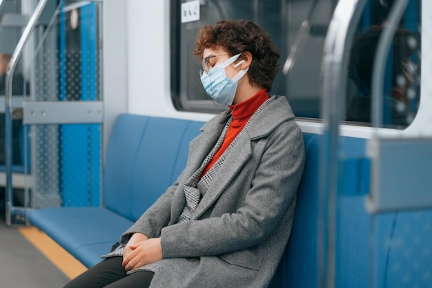 Tired woman in a protective mask fell asleep in a subway car