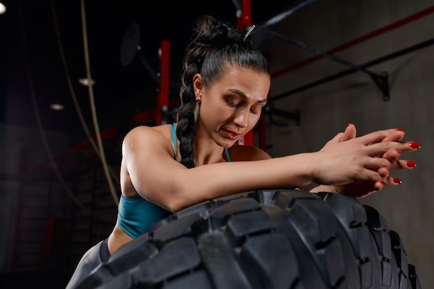 Photo tired woman resting on tire in gym