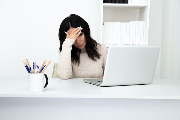 Tired woman secretary feeling bad sitting in the white office cabinet.