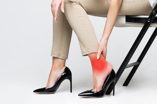 발목을 만지고 불편한 신발로 인해 다리 통증으로 고통받는 피곤한 여성