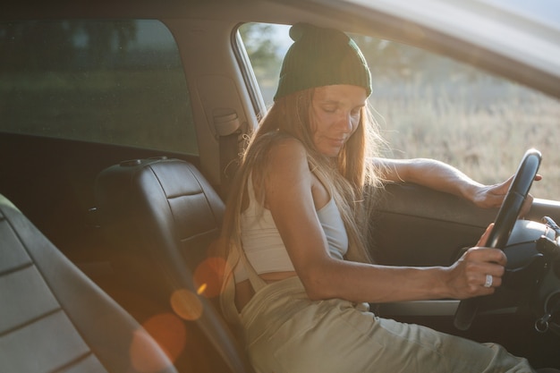 窓枠に寄りかかって、車の中で昼寝をしている時計の帽子の疲れた女性。目を閉じて。