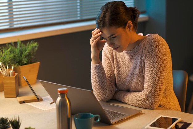 Tired woman with headache working with a laptop