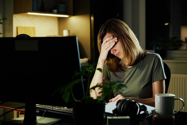 Tired woman works at home workplace