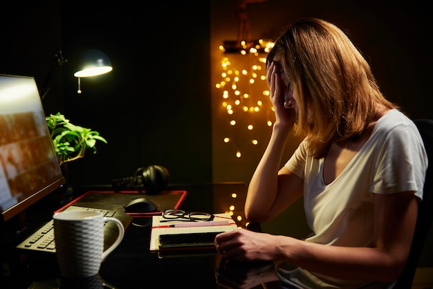 Tired woman works late at home workplace