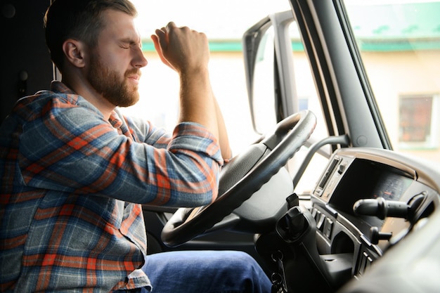 Tired of work Sitting in the cabin Young truck driver is with his vehicle at daytime