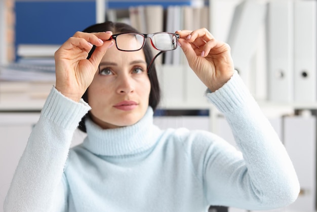 Tired worker with irritated eyes looks at glasses overworked\
woman takes off glasses to relieve