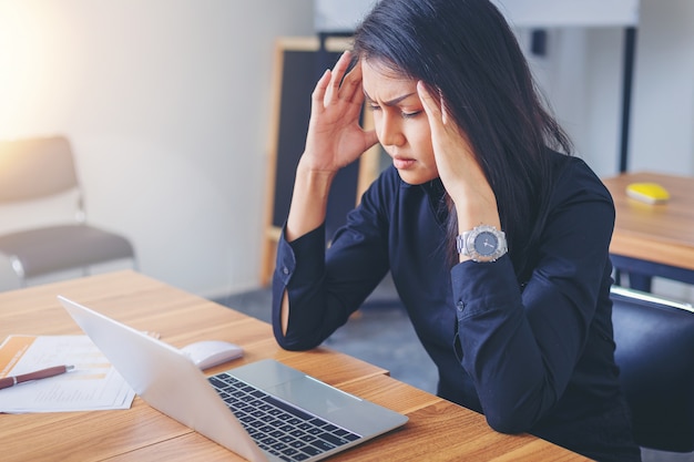 Tired working woman with headache at office.