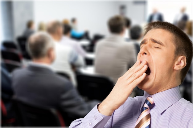 Tired Yawning Businessman on blurred office background