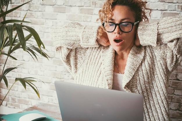 Усталая молодая взрослая женщина после переутомления с компьютером, открытым ртом для зевоты стрессовые женщины, занятые ноутбуком в онлайн-бизнесе поза боли в шее болезненная дама на работе