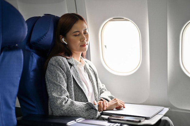 Tired young asian businesswoman eyes closed taking a nap during a flight on airplane