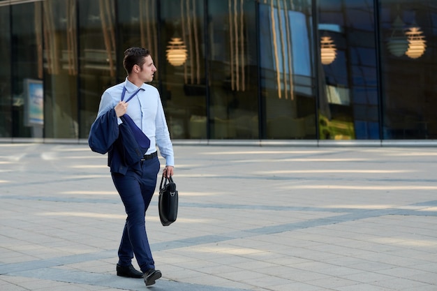 Photo tired young businessman with case going after work in hot weather