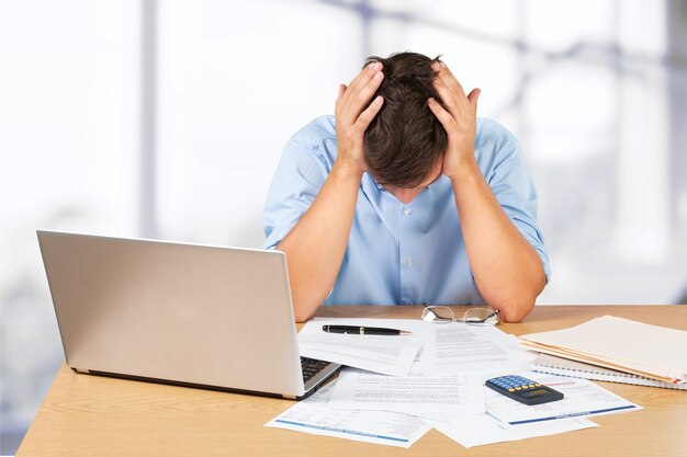 Tired young businessman with stack of papers