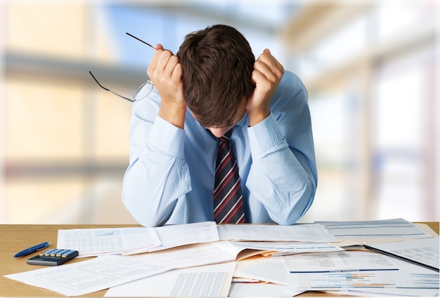 Tired young businessman with stack of papers