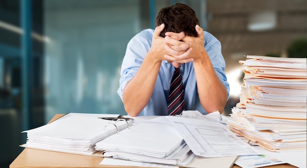 Photo tired young businessman with stack of papers