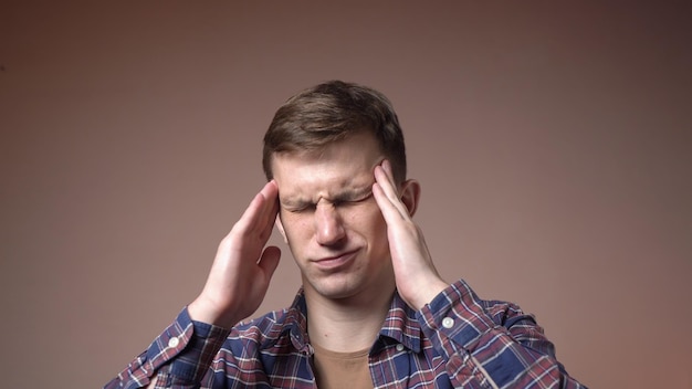 Tired young caucasian man massaging the temples of the head headache