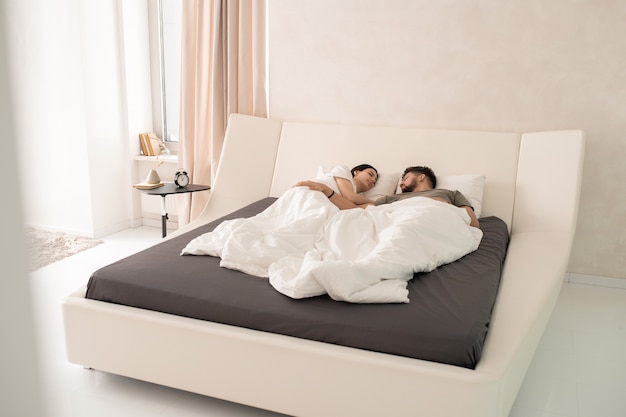 Усталая молодая пара спит в постели в гостиничном номере
