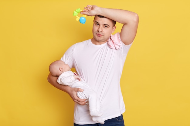 Tired young father with newborn baby in hands