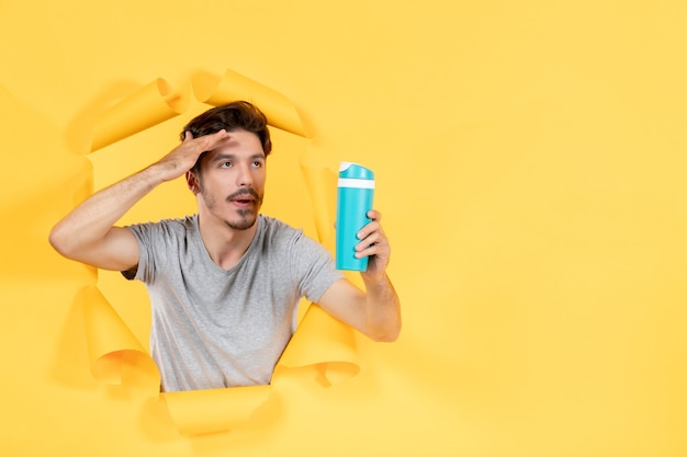 tired young male holding green bottle on a yellow background fit workout athlete gym sport
