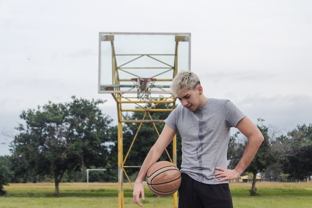 Giovane stanco su un campo da basket abbandonato.