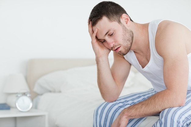 Tired young man sitting on his bed